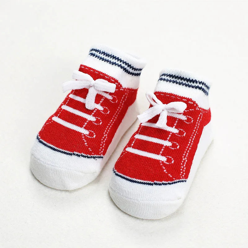 Pair of red baby socks styled like sneakers with white bows and navy stripe details, designed with anti-slip soles for toddlers and infants.